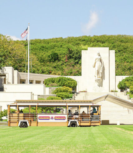 A yellow color Waikiki themed bus parked in the National Memorial Cemetery of the Pacific in Hawaii