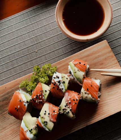 Sushi elegantly presented on a wooden board with some sauce on the table.
